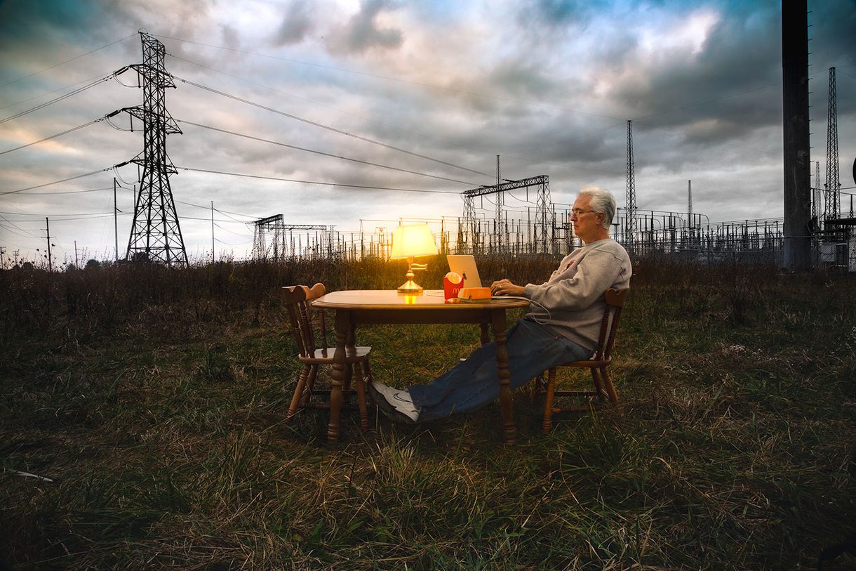 A photograph of a man working on his computer in a field taken by Nicholas Bungart, an undergraduate in Photography at CCAD.